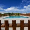 Piscina con ombrelloni bianchi, recinzione di legno.