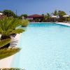 Piscina con palme e ombrelloni bianchi.