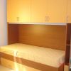 Letto singolo con armadi arancioni sopra.