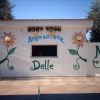 Un piccolo edificio bianco con murales di fiori e la scritta 