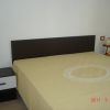 Camera da letto con letto matrimoniale e copriletto beige. Due comodini con lampade.