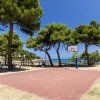 Campo da basket all'aperto vicino al mare, circondato da alberi.