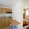 Cucina compatta con tavolo e vista su camera da letto.