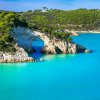 Arco naturale di roccia su mare turchese.