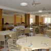 Sala da pranzo con tavoli tondi coperti da tovaglie chiare e sedie beige.
