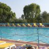 Piscina circondata da lettini gialli e alberi sullo sfondo.