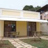 Bungalow giallo con tavoli e sedie sotto una veranda. Sentiero di pietra nel giardino.