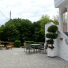 Cortile con tavolo e sedie, circondato da alberi e siepi.