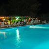 Piscina illuminata di sera, con sedie a sdraio e ombrelloni sul bordo.