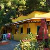 Edificio giallo con verande, circondato da piante e alberi.