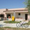 Casa rosa con veranda, giochi da piscina colorati e una bicicletta sul vialetto.
