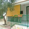 Un piccolo portico con ringhiera verde e tenda di bambù. Un albero adiacente.