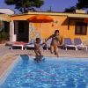 Una donna e un bambino saltano in una piscina vicino a ombrelloni arancioni.