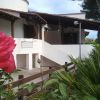 Primo piano di una rosa davanti a una casa bianca con tetto di legno.