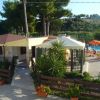 Piscina all'aperto con lettini e ombrelloni accanto a un edificio con giardino.