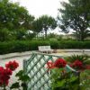 Un giardino con panchine bianche e fiori rossi in primo piano.