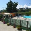 Area piscina all'aperto con lettini, ombrellone e siepi verdi.