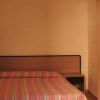Camera da letto con letto matrimoniale a righe colorate e armadio in legno chiaro.