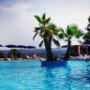 Piscina diurna con palme centrali e lettini.