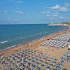 Spiaggia affollata con ombrelloni blu.