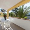 Terrazzino con tavolo bianco e piante tropicali.