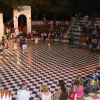Spettacolo serale all'aperto con bambini e pubblico in anfiteatro.