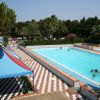 Piscina esterna con bordo decorato e alberi intorno.