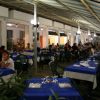Ristorante all'aperto con tavoli apparecchiati di blu.