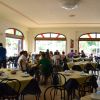 Sala da pranzo con tavoli apparecchiati, persone sedute.